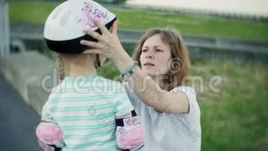 <strong>妈妈帮</strong>女儿戴上头盔和防护用具，在公园里溜冰。 女人<strong>帮</strong>助女孩