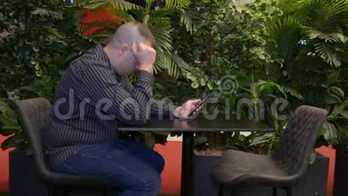 穿着长袖黑色衬衫的男人坐在<strong>夏天</strong>的咖啡馆里，通过电话进行情感交流。 外面在<strong>下雨</strong>。