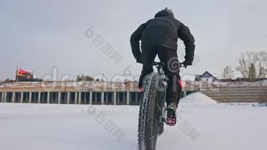 专业的极限运动员骑着一辆肥胖的自行车在户外。 骑自行车的人在冬天骑在雪冰上。 人类