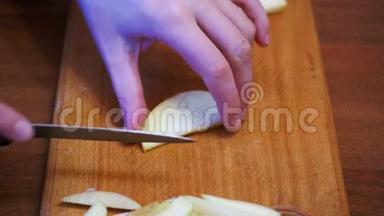 女人的手与刀切苹果在木制厨房板在家庭厨房