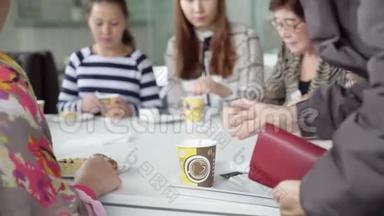 一支女队坐在咖啡馆里喝杯茶。 同事在午餐期间就不同的话题进行交流.. 女孩们在