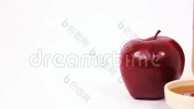 在白色背景下分离的红苹果、蜂蜜罐和一碗蜂蜜