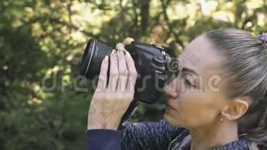 游客在森林中拍摄风景。 一个高加索女人近距离射击。 女孩在dslr上拍照