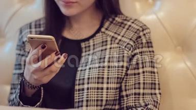 带着电话的漂亮女孩。 女人在咖啡馆的智能手机上使用应用程序。 在手机上发短信。