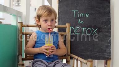 时间到DETOX粉笔铭文。 这个男孩正在喝新鲜、健康、排毒的水果饮料。 奶昔，新鲜果汁，牛奶