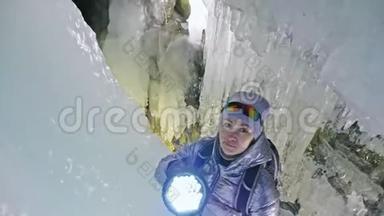 在贝加尔湖冰洞旅行的女人。 去冬岛旅行。 女孩背包客正在冰窟散步。 旅行者看起来