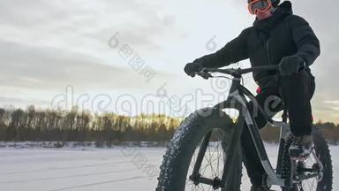 专业的极限运动员骑着一辆肥胖的自行车在户外。 骑自行车的人在冬天骑在雪冰上。 人类