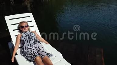 小女孩躺在<strong>日</strong>光浴床上戴着太阳镜和一条薄纱披肩。 <strong>儿童</strong>在洪水木水下码头休息。 人行道