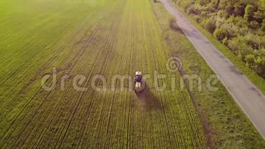 日落时用喷雾器、除草剂和杀虫剂喷洒农用拖拉机的空中景观。 农业机械