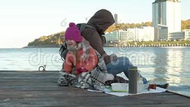 男人和<strong>女孩</strong>，父亲和女儿，坐在河港，<strong>喝茶</strong>，野餐，笑，穿着暖和的衣服
