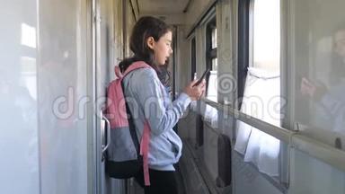 小女孩走在火车车厢里，带着生活方式、背包和智能手机。 <strong>交通运输</strong>