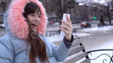 冬天，一个穿着灰色<strong>保暖</strong>夹克的年轻女人在街上用电话。
