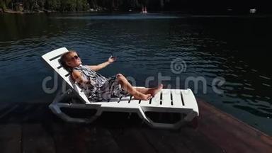 小女孩躺在日光浴床上戴着太阳镜和一条薄纱披肩。 儿童在洪水木水下码头休息。 人行道