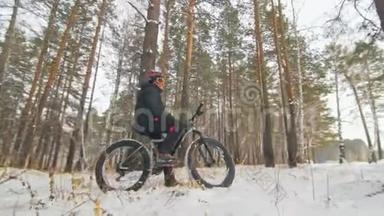 职业极限运动员骑自行车在户外坐一辆胖自行车。 骑自行车者在冬天的雪林中退缩。 与人<strong>同行</strong>