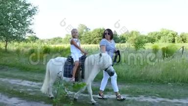 妈妈和女儿在田里走来走去，女儿骑着一匹小马，妈妈抱着一匹小马做缰绳