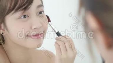 美丽的肖像年轻的亚洲女人微笑着面对镜子，在卧室里用刷子涂妆