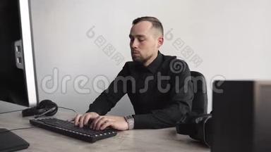 年轻的商人或穿着衬衫坐在电脑显示器旁的学生。 在办公室的一张桌子上工作