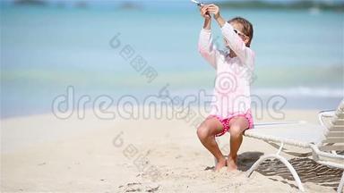 快乐的小女孩手里拿着玩具飞机在白色沙滩上。 小孩在海滩上玩玩具