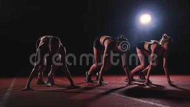 田径场的女跑运动员在比赛前蹲在<strong>起点</strong>。 动作缓慢。