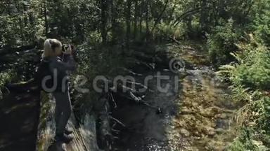 游客在森林河拍摄风景。 木桥倒树.. 一个白种人女人用漂亮的魔法