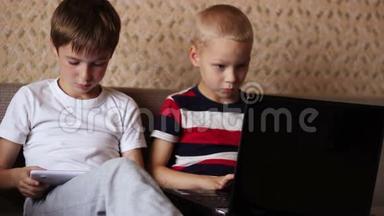 两个男孩在家玩平板电脑和笔记本电脑