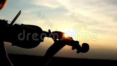 剪影女孩<strong>小提琴</strong>手在日落的天空背景下拉<strong>小提琴</strong>。