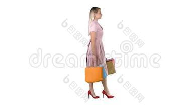 快乐的漂亮女孩拿着白色背景上的购物袋走路。