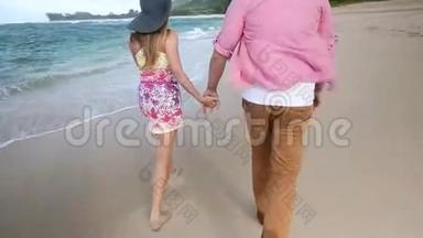 可爱的白种人年轻夫妇牵着手在夏威夷瓦胡岛海滩散步