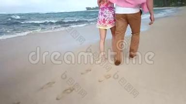 可爱的白种人年轻夫妇牵着手在夏威夷瓦胡岛海滩散步