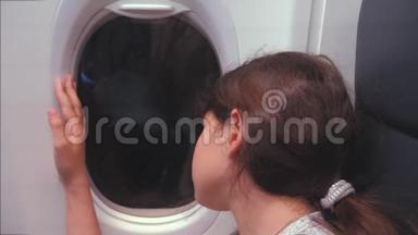 <strong>航空飞机</strong>概念。年轻女孩坐在窗边看着外面的飞机。夜间飞行生活方式