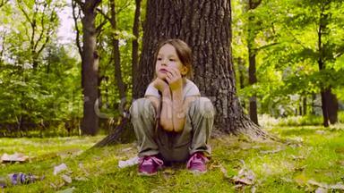 一个女孩坐在公园的草地上靠近树