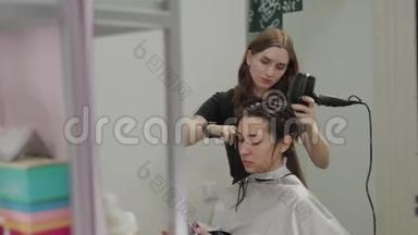 女理发师用<strong>吹风机</strong>给客户理发。