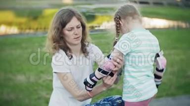 妈妈帮女儿戴上头盔和防护用具，在公园里溜冰。 女人帮助女孩