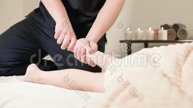 男理疗师按摩师为躺在按摩床上的小孩做一个舒缓足部按摩