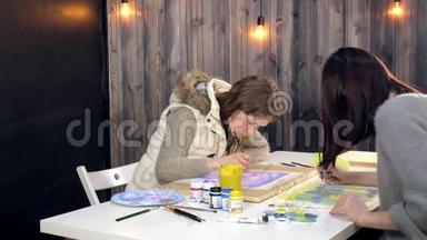 两名成年女子在<strong>艺术学校</strong>用彩色丙烯酸颜料作画