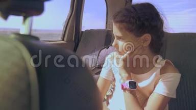 悲伤的女孩无聊地坐在后座的车里。 小女孩在车里无聊。 <strong>长途旅行</strong>