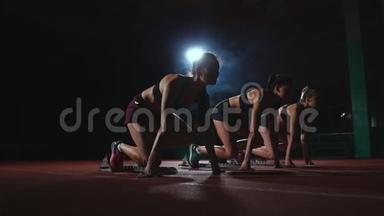田径场的女跑运动员在比赛前蹲在起点。 动作缓慢。
