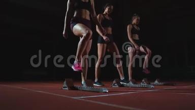 田径场的女跑运动员在比<strong>赛前</strong>蹲在起点。 动作缓慢。
