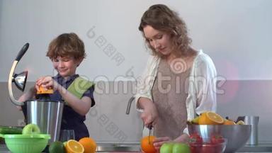 年轻的白种人母亲和孩子在厨房用电<strong>榨汁</strong>机制作<strong>鲜</strong>橙果汁
