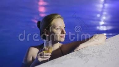 晚上的女人在泳池里<strong>喝</strong>着<strong>热水喝</strong>着一杯香槟