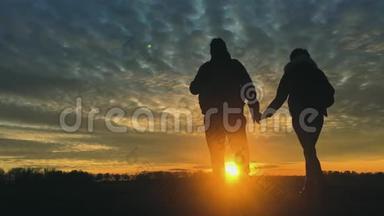 两个徒步旅行者的剪影带背包，从山顶欣赏日落景色。 享受日落美景