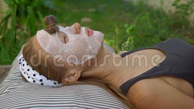 年轻女人用蜗牛粘液做面膜。 在面具上爬行的蜗牛