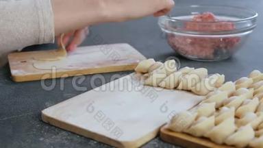 女人用肉馅包饺子，特写的手。