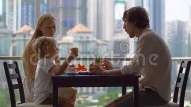 年轻的<strong>一家人</strong>在摩天大楼的阳台上<strong>吃早餐</strong>、午餐，可以看到整个市中心