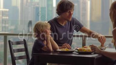 年轻的<strong>一家人</strong>在摩天大楼的阳台上<strong>吃早餐</strong>、午餐，可以看到整个市中心