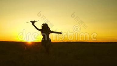 快乐<strong>的</strong>女孩带着玩具飞机在夕阳下<strong>的</strong>田野上<strong>奔跑</strong>。 孩子们玩玩具飞机。 <strong>少年</strong>梦想