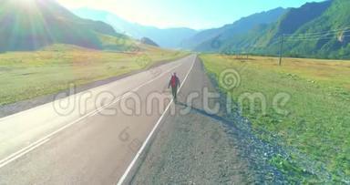 乘坐搭便车游客在沥青路上行走。 夏日的乡村山谷。 背包徒步旅行者。
