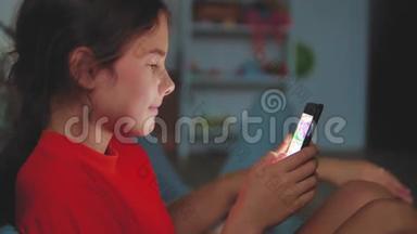 有智能手机的小女孩躺在床上睡觉。 在家里上网玩智能手机网络游戏的小女孩