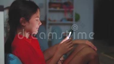 有智能手机的小女孩躺在床上睡觉。 在家里上网玩智能<strong>手机网</strong>络游戏的小女孩