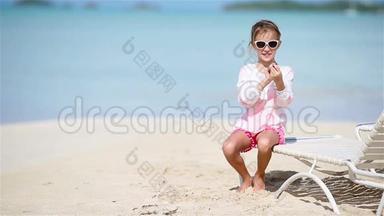 快乐的小女孩手里拿着玩具飞机在白色沙滩上。 小孩在海滩上玩玩具